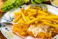 Portion of delicious homemade battered fish and french fried with metal fork in white ceramic dish Royalty Free Stock Photo