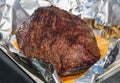 Portion of foil wrapped spicy seasoned beef brisket with juices