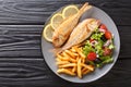 Portion of fried pink dorado fish with french fries and vegetable salad closeup on a plate. horizontal top view