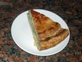 A portion of a healthy vegetable pie on a white plate with a dark background of brown granite