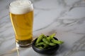 Portion Japanese Edamame soy beans in porcelain bowl with beer glass on marble background Royalty Free Stock Photo