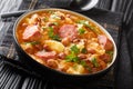 Portion of Jota sauerkraut with borlotti beans, potatoes and sausages close-up in a bowl. horizontal