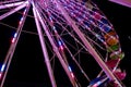 Portion of a lighted Ferris wheel at night with multicolored gondolas