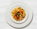 portion of mac and cheese with corn, bacon topped with panko breadcrumbs on white plate on white wooden table Royalty Free Stock Photo