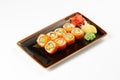 A portion of maki sushi with an assortment of Japanese side dishes in a rectangular ceramic plate Royalty Free Stock Photo