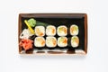 A portion of maki sushi with an assortment of Japanese side dishes in a rectangular ceramic plate on a white plate Royalty Free Stock Photo