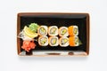 A portion of maki sushi with an assortment of Japanese side dishes in a rectangular ceramic plate on a white plate. Royalty Free Stock Photo