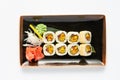 A portion of maki sushi with an assortment of Japanese side dishes in a rectangular ceramic plate on a white plate. Royalty Free Stock Photo