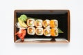 A portion of maki sushi with an assortment of Japanese side dishes in a rectangular ceramic plate on a white plate. Royalty Free Stock Photo
