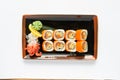 A portion of maki sushi with an assortment of Japanese side dishes in a rectangular ceramic plate on a white plate. Royalty Free Stock Photo