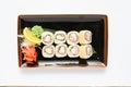 A portion of maki sushi with an assortment of Japanese side dishes in a rectangular ceramic plate on a white plate. Royalty Free Stock Photo