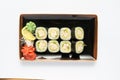 A portion of maki sushi with an assortment of Japanese side dishes in a rectangular ceramic plate on a white plate. Royalty Free Stock Photo