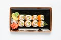 A portion of maki sushi with an assortment of Japanese side dishes in a rectangular ceramic plate on a white plate. Royalty Free Stock Photo
