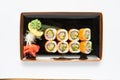 A portion of maki sushi with an assortment of Japanese side dishes in a rectangular ceramic plate on a white plate Royalty Free Stock Photo