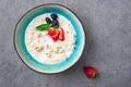 Portion of oatmeal porridge with strawberry, blueberry, mint in bowl