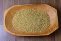 Portion of raw brown rice, wooden bowl, wooden table top view