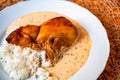 Portion of roasted chicken with dill sauce and stewed rice on plate