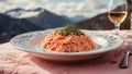 portion of salmon risotto in an embroidered plate on a pink tablecloth in front of a Norwegian fjord