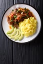 Portion of seco de chivo stewed goat meat with yellow rice and a