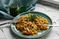 Portion of spaghetti pasta like noodles with fried vegetables on a modern plate in turquoise color, with green sauce in a jar, the Royalty Free Stock Photo