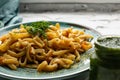 Portion of spaghetti pasta like noodles with fried vegetables on a modern plate in turquoise color, with green sauce in a jar, the Royalty Free Stock Photo