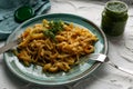 Portion of spaghetti pasta like noodles with fried vegetables on a modern plate in turquoise color, with green sauce in a jar, the Royalty Free Stock Photo