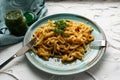 Portion of spaghetti pasta like noodles with fried vegetables on a modern plate in turquoise color, with green sauce in a jar, the Royalty Free Stock Photo