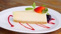Portion of vanilla cheese cake with fresh strawberry sauce is served on a white plate
