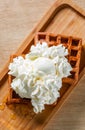 Portion of Viennese wafers with cream and ice cream on wooden table