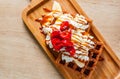 Portion of Viennese waffle with cream, strawberry, banana, caramel and ice cream on wooden table