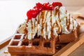 Portion of Viennese waffle with cream, strawberry, banana, caramel and ice cream on wooden table