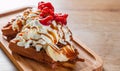 Portion of Viennese waffle with cream, strawberry, banana, caramel and ice cream on wooden table