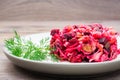 A portion of vinaigrette - a salad of boiled vegetables, sauerkraut and pickled cucumbers on a plate on a wooden table. National