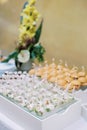 Portioned salads in cups with spoons on a tray next to mini-burgers are on the table Royalty Free Stock Photo