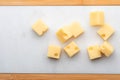 Portions cubes, dice of Emmental Swiss cheese . Texture of holes and alveoli. On white marble table