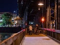 Cyclists standing at night in front of a closed barrier of a draw bridge