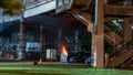 Garbage contained on fire on a parking space under Steel bridge. Royalty Free Stock Photo