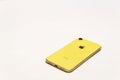 PORTLAND, OR / USA - MARCH 31 2020: Yellow Apple iPhone XR on White Background Isolated Flat Layout. Back view of smart mobile