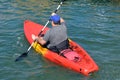 Portly Gentleman Paddling a Bright Orange Kayak Royalty Free Stock Photo