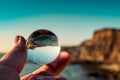 Porto Barril beach with selective focus through a lens ball reversing cliff by the sea with defocused background