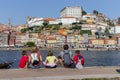 Family back view sitting on embankment of river Douro, Porto, Portugal. Tourists in Portugal. Backpackers on aerial view of Porto.