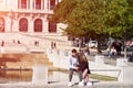 PORTO, PORTUGAL - MARCH 26, 2018: Young Couple sitting on a bench, Guy with browsing internet on smartphone