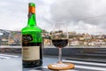 Glass and bottle of port wine with blurred cityscape of Porto Portugal in the background