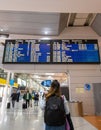 Porto, Portugal: November 13 2022. Young woman standing with her backpack looks at schedule on airport station. Themed public