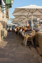 Outdoor cafe with people on the street. People sitting under big umbrellas in cafe terrace. Porto landmark.