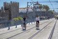 Two men cycling on railroad tracks of the subway on the D. Luis Bridge, medieval wall and monastery as background