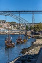 View of river Douro, with tourists, Rabelo boats on docks, transport for Porto Wine, D. Luis bridge and Porto city as background Royalty Free Stock Photo