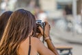 View of two girls sitting on an outdoor terrace, one of them takes photo with camera