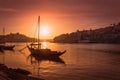 Porto at sunset: Duoro river with rabelo boat in front of setting sun and Arrabida bridge in background, Portugal Royalty Free Stock Photo