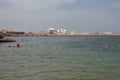 Porto Torres, Italy - Jul 06, 2019: Bay with bathing people next to seaport